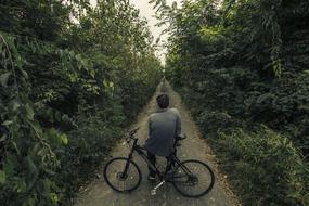 a man is resting while sitting on a bicycle in the thicket