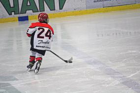 Child in colorful clothing playing ice hockey in Slovakia