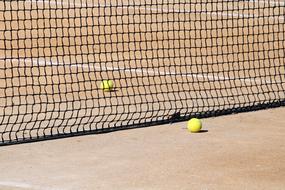 tennis balls next to the black net