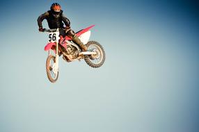 Person, on the motocross bike, in jump, at background with the sky