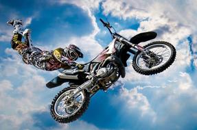 motorcycle stuntman against the background of cumulus clouds