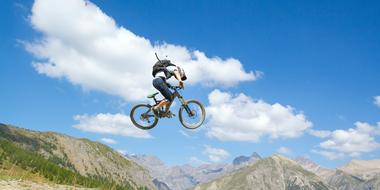 athlete jumping with a bicycle on a background of mountains
