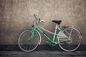 green bike stands against a gray wall