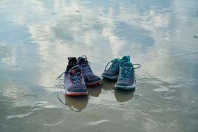 two pair of sports Shoes with Reflection on wet beach