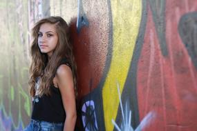 photo of teenage girl by the wall with graffiti