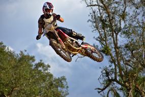young boy jumps at sky while riding motorcycle, low angle view
