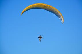 athlete with a yellow paraglider on a blue sky background