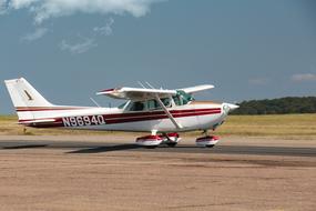 Red and white "M17" sport aircraft on the lane, among the colorful fields