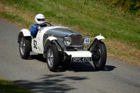 sportsman on retro racing car rides downhill