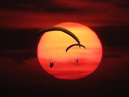 People doing parachuting at background with colorful Sun