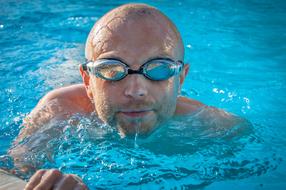 bald man swims in the pool