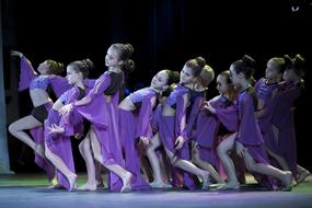 a group of girls is dancing in purple dresses