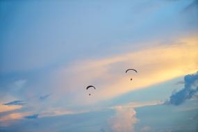 distant view of paragliders at colorful sky with the clouds