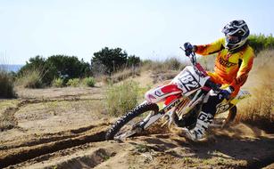 Person in colorful costume and helmet, riding on the bike, on the motocross competition