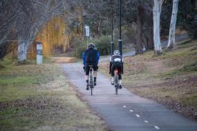 two athletes in helmets ride bikes on path in park