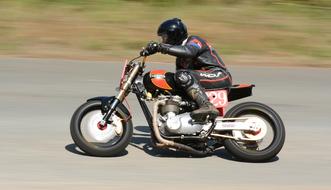Person on the colorful motorbike in motion, on the road, near the colorful field, on the hillclimb competition