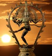 Shiva Goddess dancing, bronze figurine at sunset sky