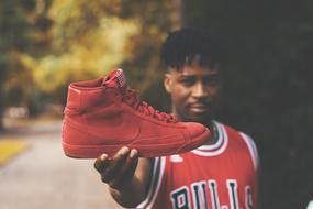 athlete holds red nike sneakers in his hand