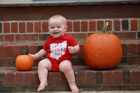little boy among two pumpkins