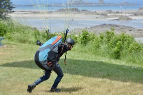 Paraglider with the equipment, on the colorful meadow, in light, near the water, in France