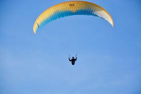 Paraglider on the colorful parachute in the blue sky, on the Ozone Wing Rush 5