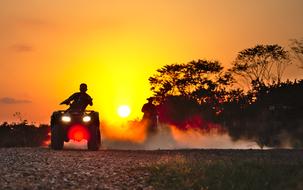 boy speeding Quads and horse rider on soil road at sunset