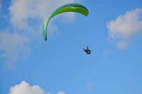 athlete flies on a green parachute in the blue sky
