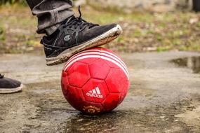 soccer player holds red ball with his foot