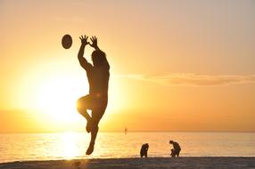 Sport on Beach at sunset, male silhouette in jump