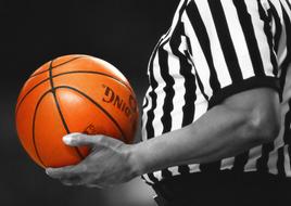 brown basketball ball in the hands of the referee