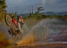Person riding on the motorcycle, in the water, among the colorful plants