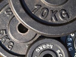 Close-up of the shiny, metal weight plates, with the numbers and signs