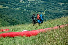 parachutes landed on a green hill with beautiful hills on background