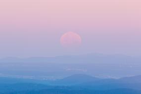 blue mountains and moon against pink sky