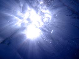 white splash at blue surface, sun through water