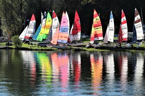 Colorful and beautiful sailing boats, with reflections in the water, near the green shore