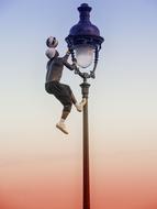 man with ball on street lamp
