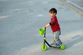 little boy riding a green scooter