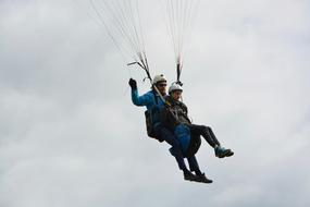 tandem Paragliding, young people at cloudy sky