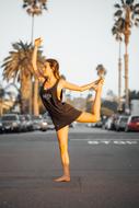 young girl doing Yoga exercise on road at evening