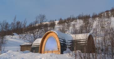 Beautiful, wooden snowhotel, in white snow, among the trees, in Kirkenes, Norway, in the winter