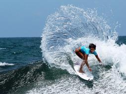 Girl in blue clothes surfing on the water with splashes