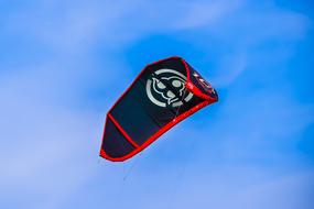 Black, white and red parachute for kite surfing, at blue sky with white clouds