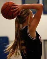 Blonde basketball player, in uniform, throwing the ball