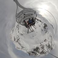 three skiers in Chairlift above snowy mountain