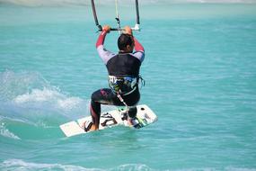 Man, doing kitesurfing on the beautiful, turquoise water