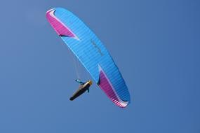 Beautiful, blue and purple parachute for paragliding, in the beautiful blue sky