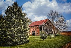 Beautiful, old, rustic barn, among the colorful fields and trees in Ohio, USA, under the blue sky with white clouds