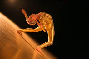 Orange and yellow figure in performance, at dark background, on clipart