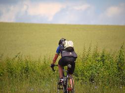 a cyclist in a helmet rides a green field